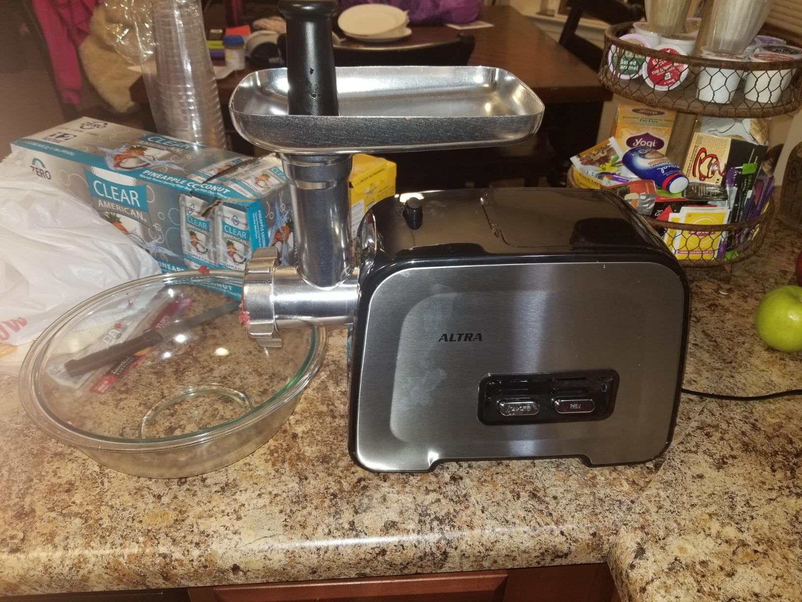 Altra meat grinder ready to use on a kitchen counter with an empty glass bowl beside it