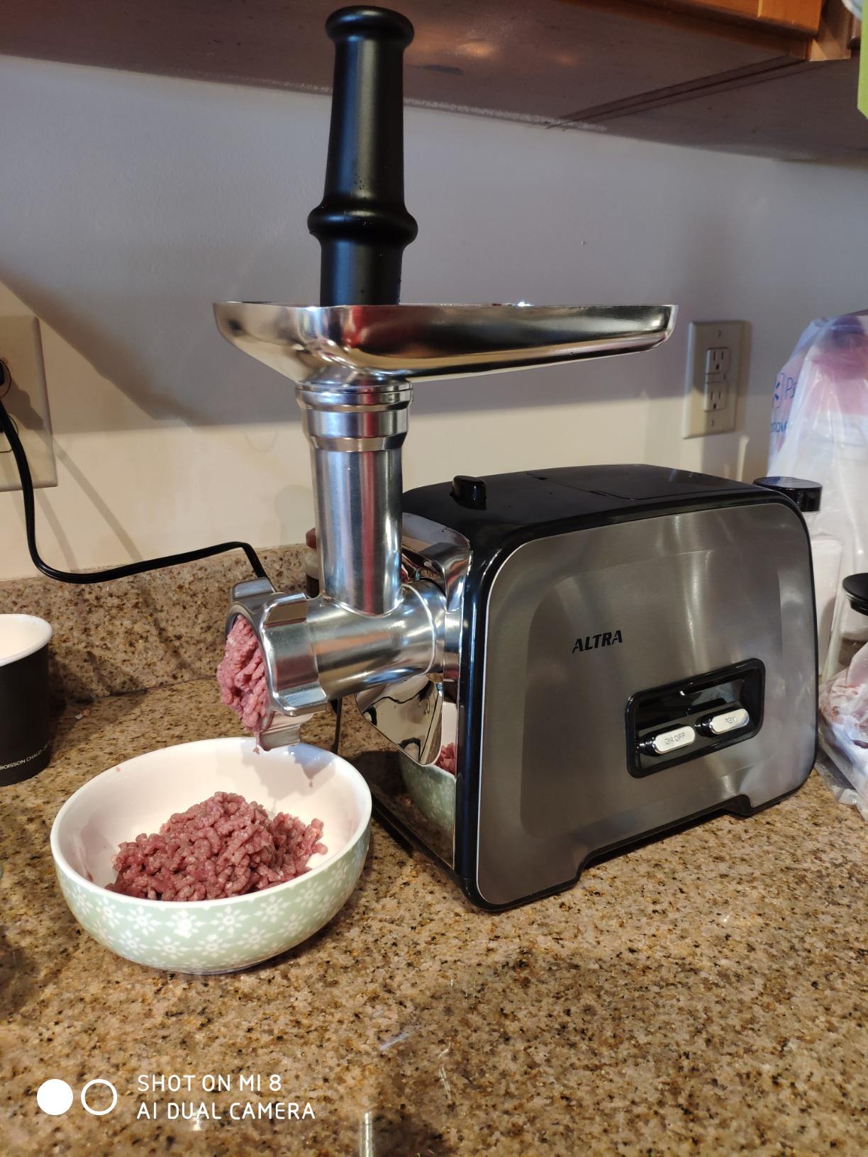 Altra meat grinder on a granite countertop with a small bowl of ground beef under the grinding head