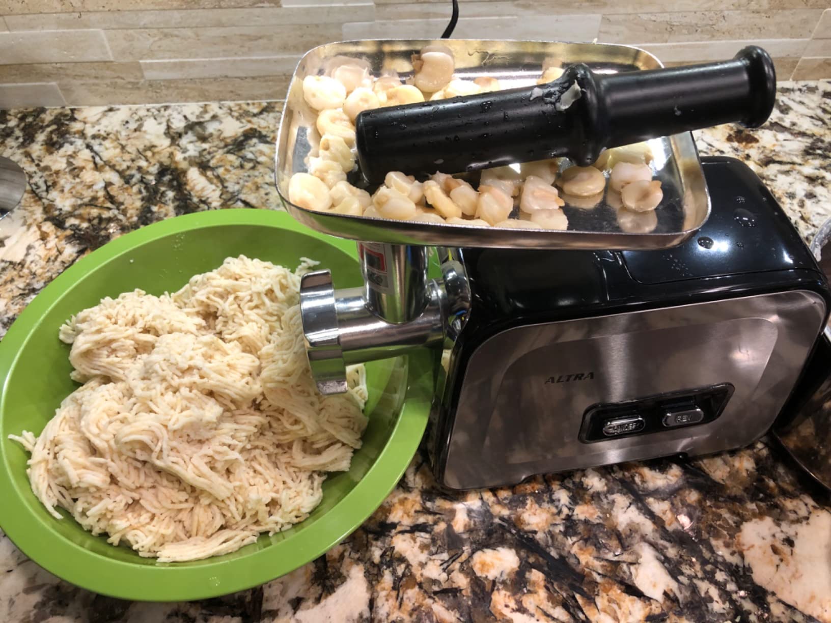 Chicken pieces in the Altra grinder tray and a green bowl of shredded chicken next to the grinding head
